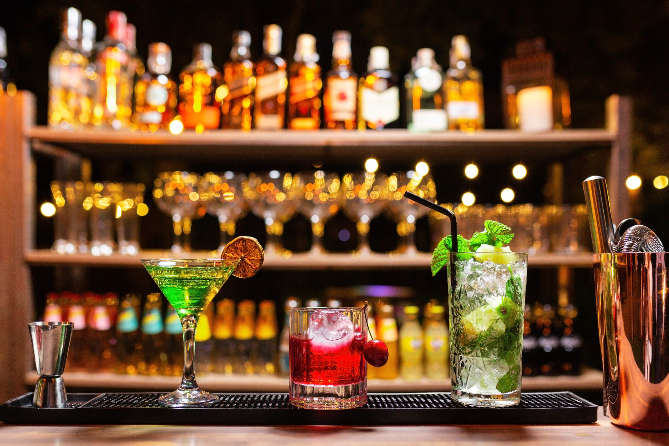 three alcoholic cocktails, cherry, lime and mint mojito in a bar